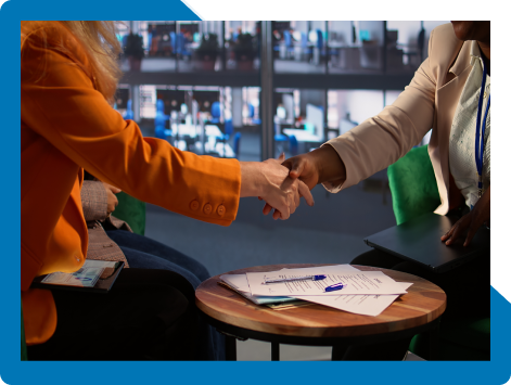 Two professionals shaking hands over documents, representing the predictable, low-risk delivery Bamshaw offers partners and customers