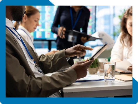 Badged team reviewing data on a tablet in a meeting, representing Bamshaw operating in regulated, compliance-driven environments